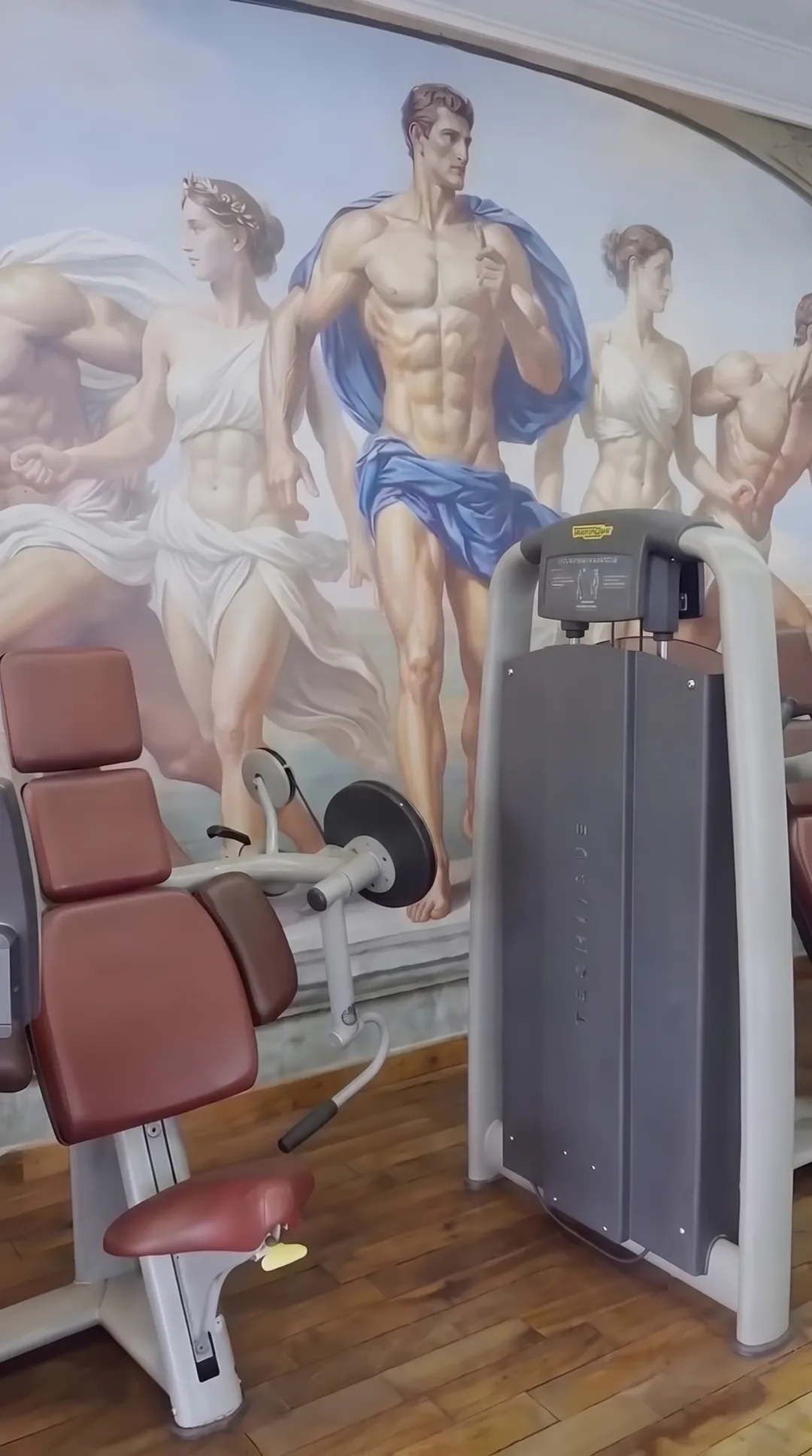 A classical mural of athletes above the training machines